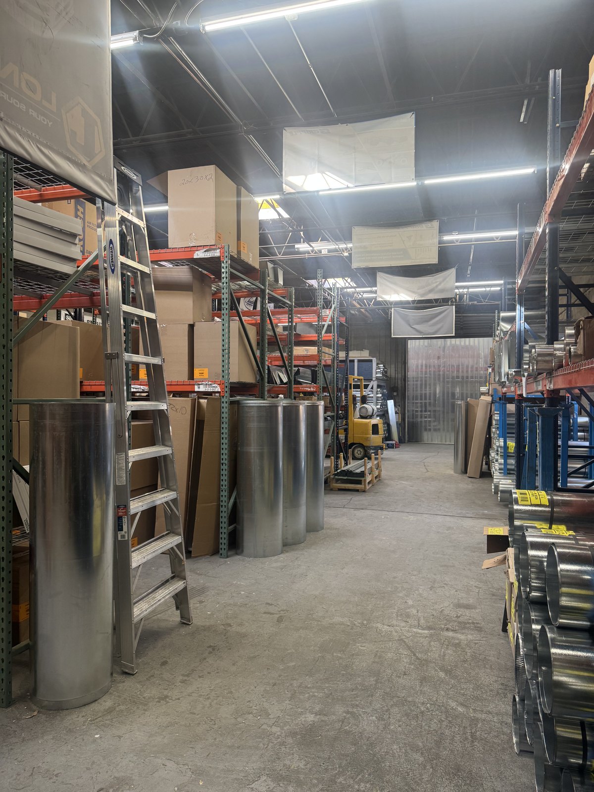 Warehouse aisle with sheet metal duct and fittings in stock